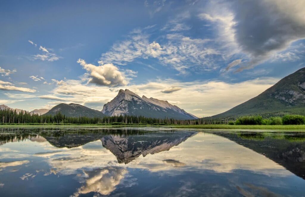 Serene landscape of Banff National Park with mountains and lake reflections at sunrise.