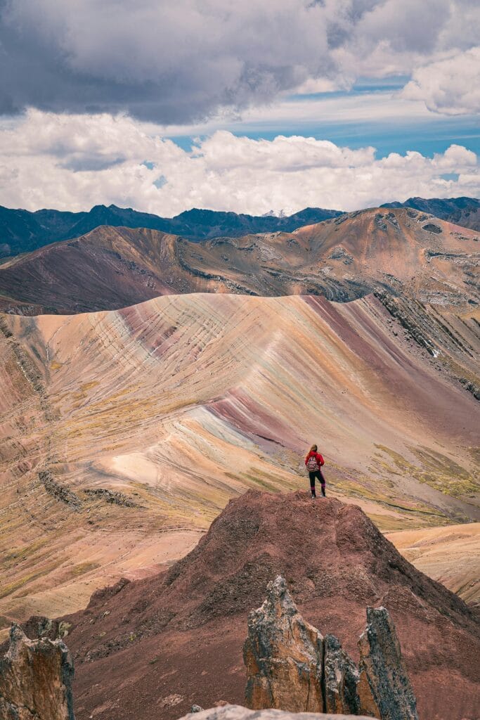 Adventurous hiker atop the vibrant peaks of Rainbow Mountain, Peru during daytime.