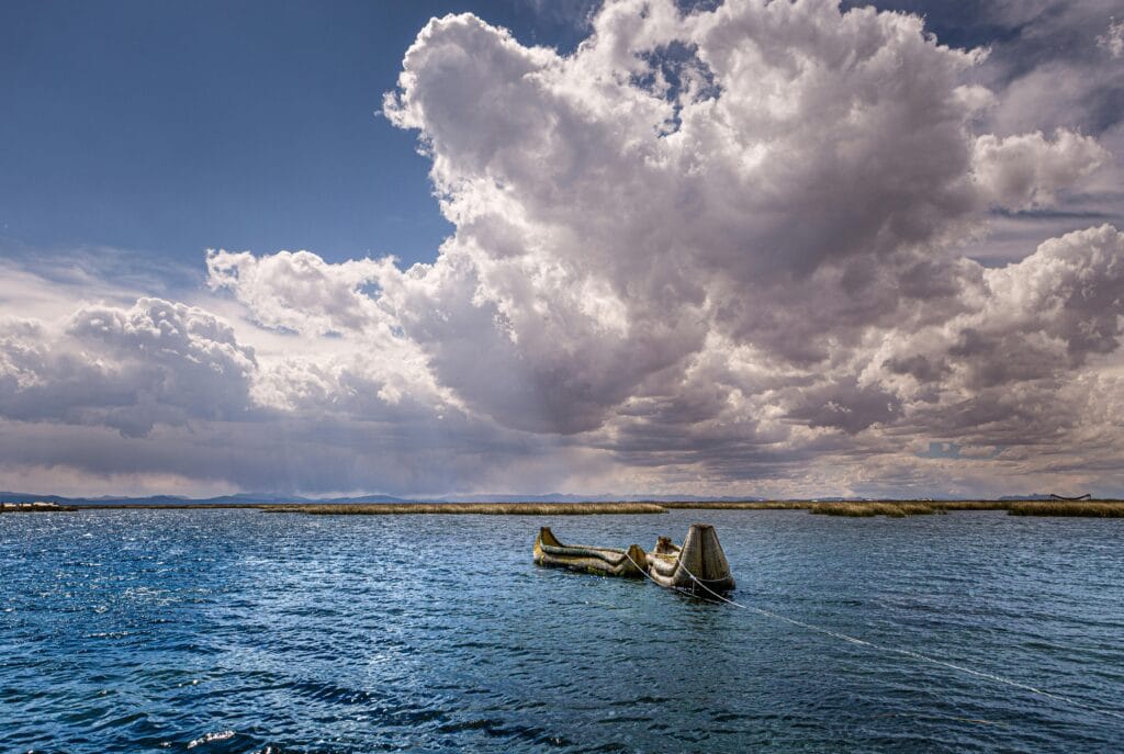 A serene view of a canoe on a lake under dramatic clouds in Peru.